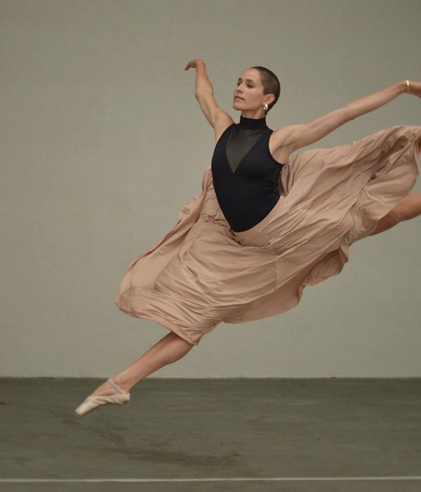 Woman performing a dynamic cardio movement in a dark studio.